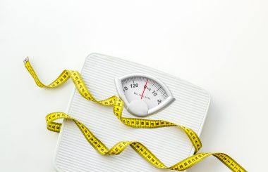 Diet. Bathroom scales and measuring tape for weight loss concept on white background top view